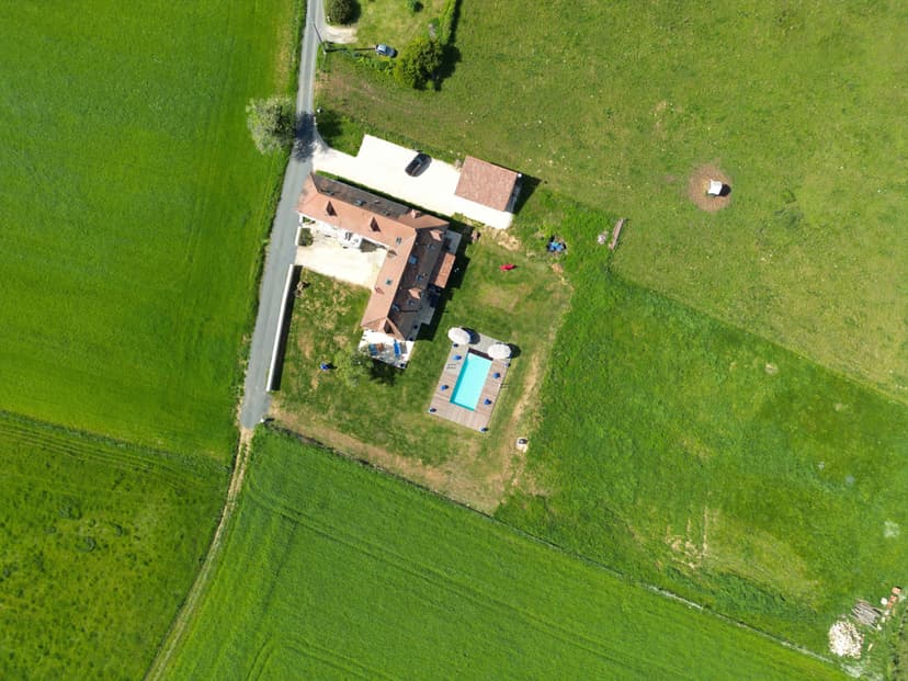 Aerial view of a luxury villa in Dordogne with private swimming pool, surrounded by lush green meadows