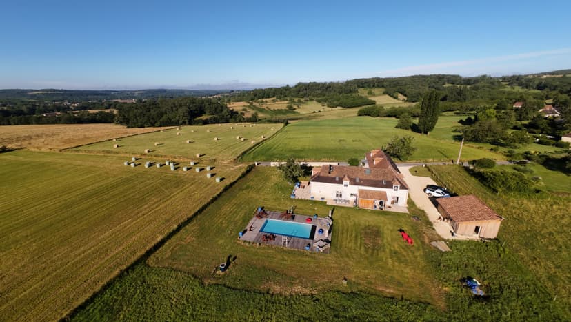 Luftaufnahme einer Ferienvilla in der Dordogne mit Pool, umgeben von Feldern und grünen Hügeln