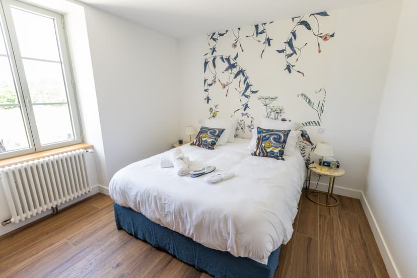 Modernes Zimmer mit Doppelbett, weißen Wänden mit gemalten floralen Motiven und Holzparkett