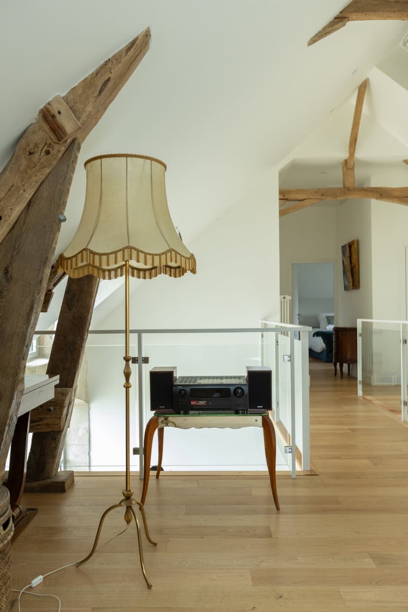 Salón moderno con vigas de madera a la vista, lámpara de pie vintage y entresuelo en propiedad de lujo en Dordoña