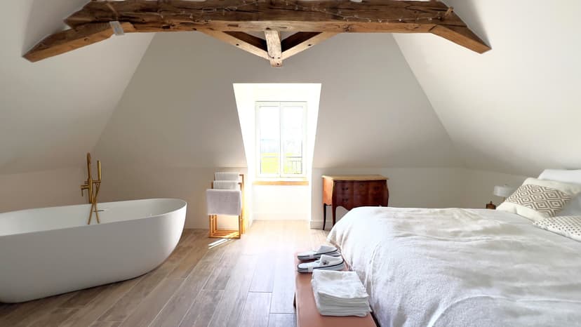 Quarto luxuoso sob telhado com vigas aparentes, banheira de design e pavimento em madeira em propriedade na Dordonha