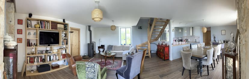 Ruime woonkamer met zichtbare balken, houten trap, open keuken en eigentijdse inrichting in de Dordogne
