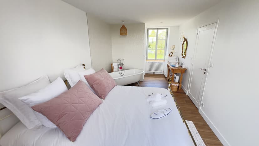 Elegantes Zimmer mit Doppelbett, freistehender weißer Badewanne und Holzwaschtisch in Luxusanwesen in der Dordogne