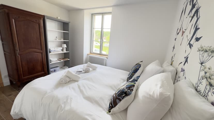 Geräumiges Schlafzimmer mit Doppelbett, antikem Schrank, Bücherregal und Fenster zur Landschaft der Dordogne