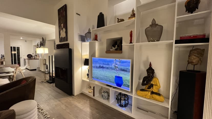 Contemporary lounge with integrated TV, white bookcase, Buddha statues and Asian décor in Dordogne villa