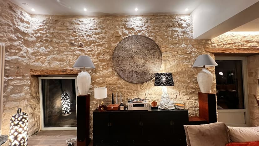 Eleganter Wohnbereich mit Steinwänden, modernem Kamin, Designlampen und handwerklicher Dekoration in einer Luxusvilla