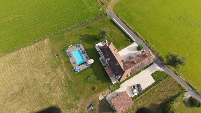 Vista aérea de una villa de lujo con piscina privada rodeada de campos verdes en Dordoña, Francia