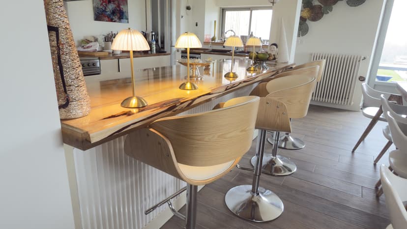 Cozinha aberta com ilha central em madeira, bancos design e candeeiros suspensos numa villa de luxo na Dordonha