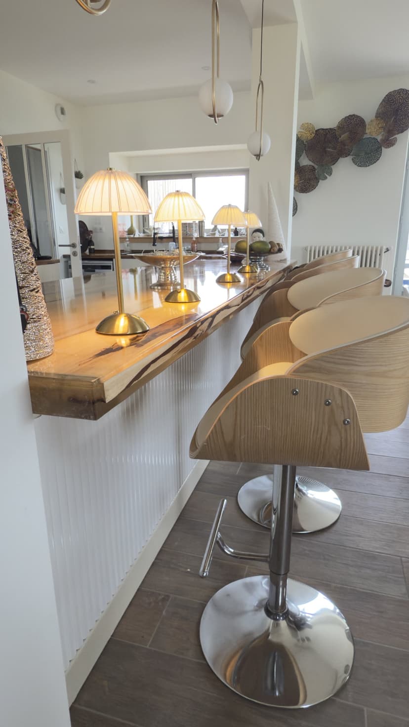 Cocina abierta con isla central de madera, taburetes de diseño y lámparas doradas en villa de lujo en Dordoña