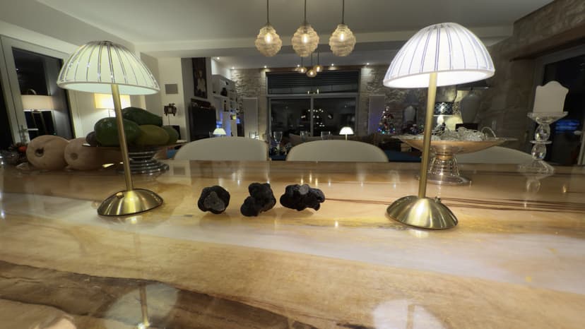 Marmeren kookeiland met designlampen en decoratieve objecten in open keuken van luxe villa